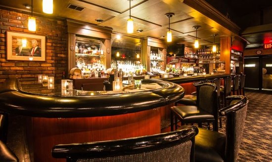 The warm, candlelit bar at Mr. Paul's Chophouse, brick walls and back-bar bottles glowing amber.
